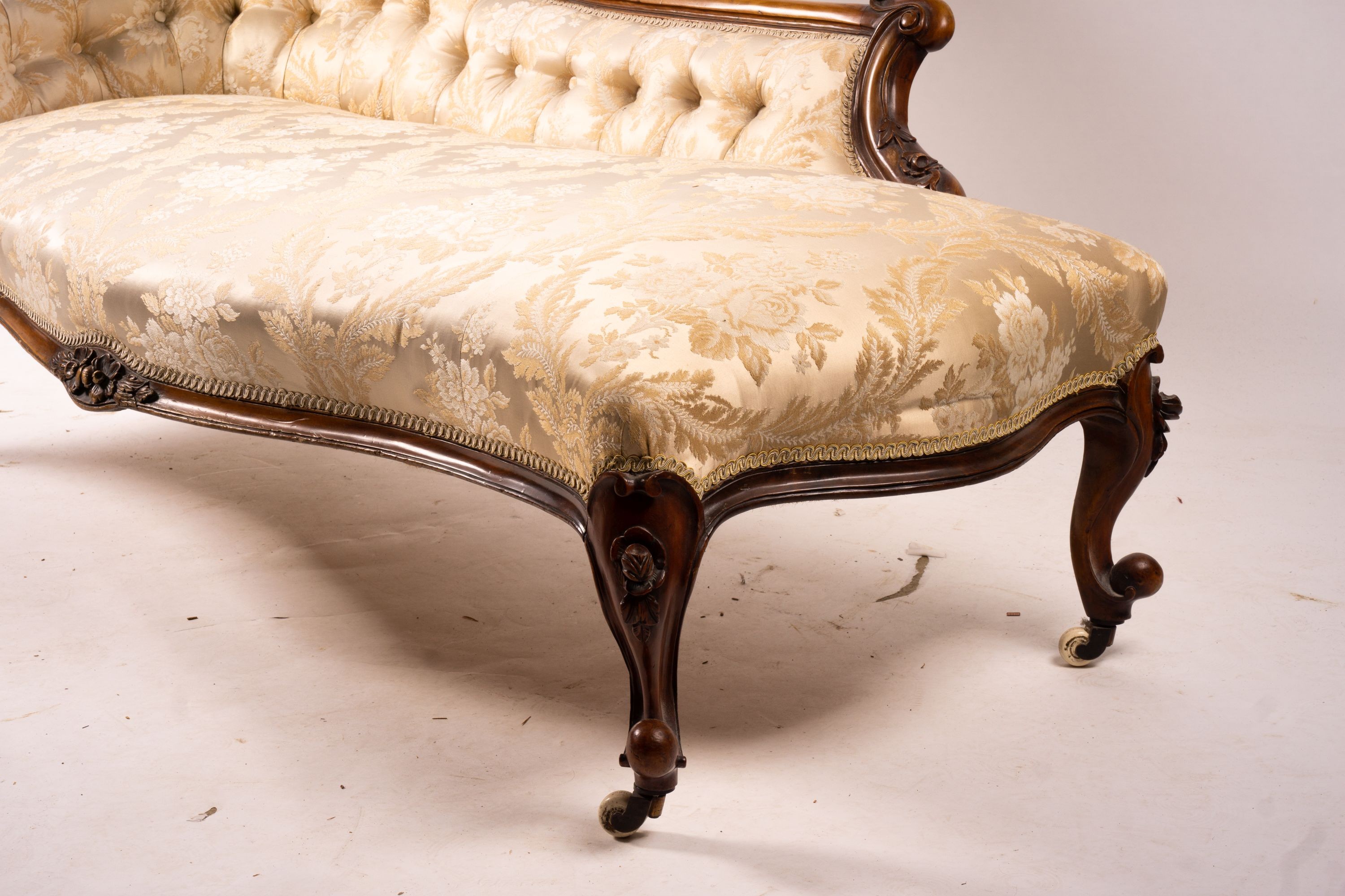 A late Victorian carved walnut three piece salon suite, comprising chaise longue, open armchair and nursing chair